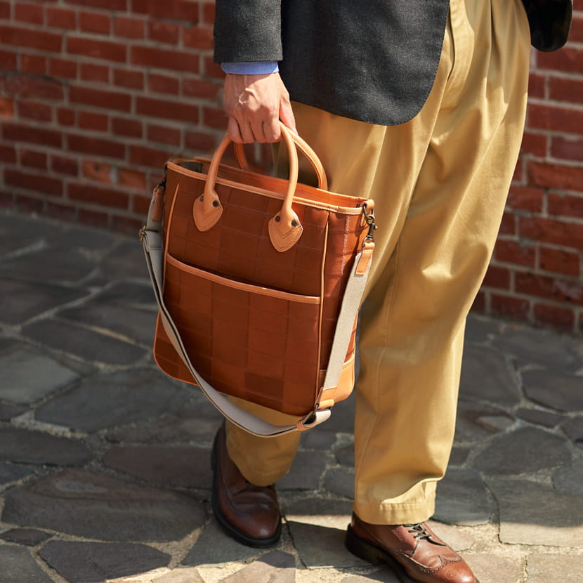 TRIONのレザートートバッグ縦型を男性が着用